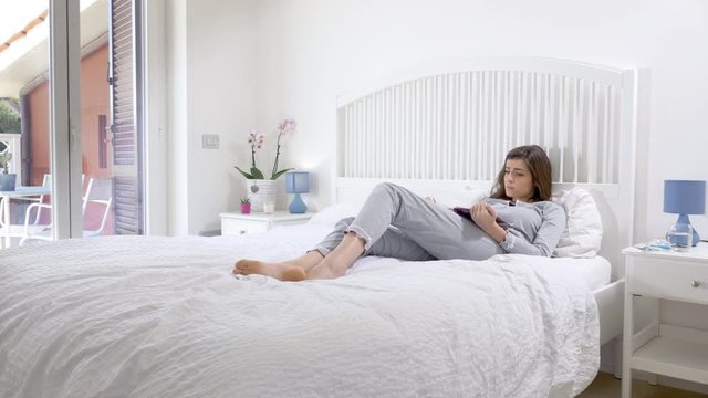 Happy woman reading book in bed in the morning at home