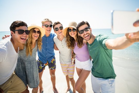 Cheerful young friends taking selfie at beach