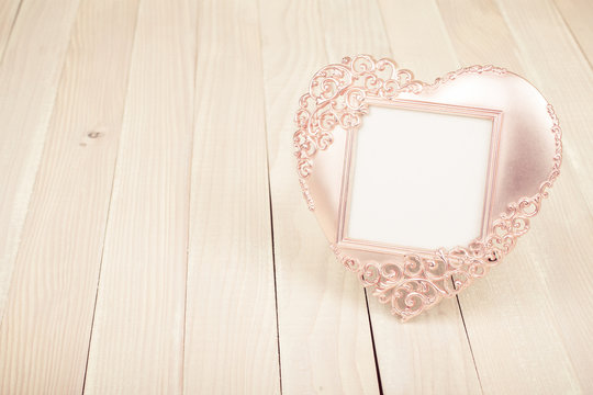 Heart shaped photo frame on wooden table
