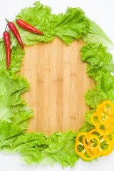 Copy space on a wooden or bamboo background, covered with vegetables, lettuce, red cabbage, red and yellow pepper. You can write here your menu or any inscription