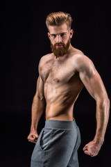 Fototapeta na wymiar shirtless bearded bodybuilder posing isolated on black in studio