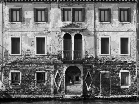 Old building in Venice on canal with eroded bricks many windows