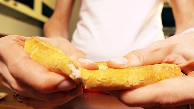Woman torning a piece of fresh french bread. Close-up slow motion shot