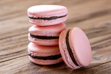 Pile of four french desert pink macaron cakes isolated on wooden background