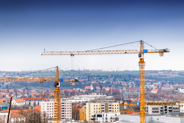 Industrial background with construction cranes over blue sky