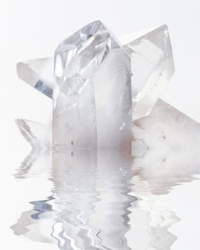 Transparent rock crystals on white reflected in a water