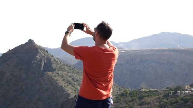 Man recording video, taking photo of canyon in mountains, super slow motion 240fps

