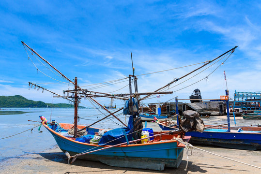 Fishing boats aground on the beach over cloudy sky at Prachuap Khiri Khan, Thailand.
