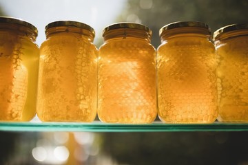 Honey and comb in glass jars on shelf