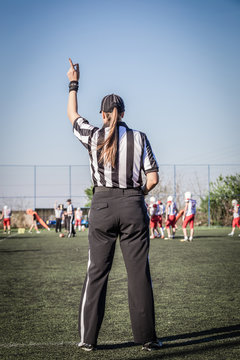 Female American football referee and blurred players in the background