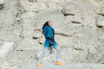 Young woman posing and dancing near the beautiful mountains dressed colorful clothes