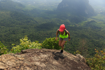 Obraz premium Young fitness woman trail runner running at mountain top