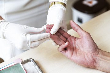 Fototapeta na wymiar Close up of nurse hands doing blood testing on man's hand