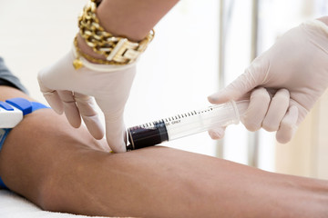 Doctor drawing blood sample from arm for blood test