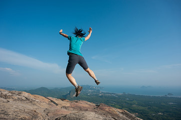 jumping on rocky mountain peak, freedom, risk, challenge, success concept