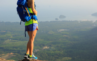 successful woman hiker enjoy the view on mountain peak cliff