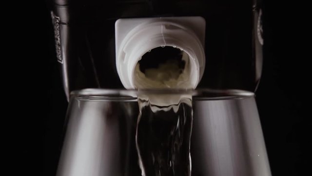 Boxed white wine pours into the glass. Slow Motion. Front view
