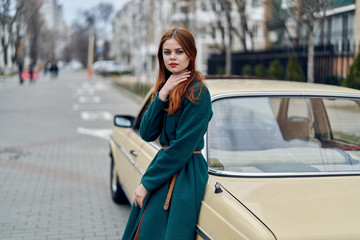 Fototapeta premium woman in green coat leans on trunk of car