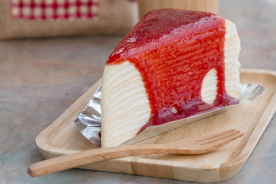 Crepe cake with strawberry sauce in wooden tray on the table