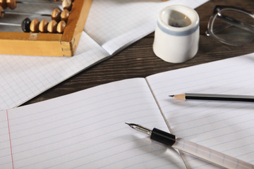 A penholder  with a pen and a simple pencil lie on an open notebook. View from above. Close-up