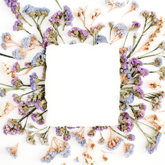 Obraz na płótnie Canvas Empty white paper blank on blue and purple dried flowers frame on white background. Flat lay, top view