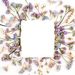 Empty white paper blank on blue and purple dried flowers frame on white background. Flat lay, top view