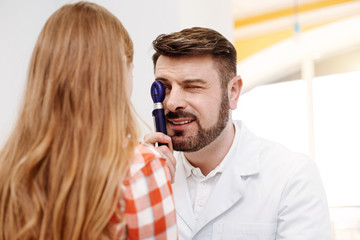 Pleasant friendly doctor studying eyes carefully