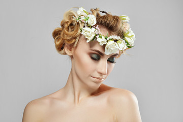 Fashion beauty model girl with flowers in her hair. Perfect creative make up and floral art hairstyle.