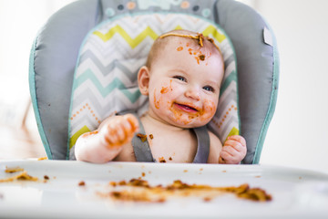 Little baby eating her dinner and making a mess