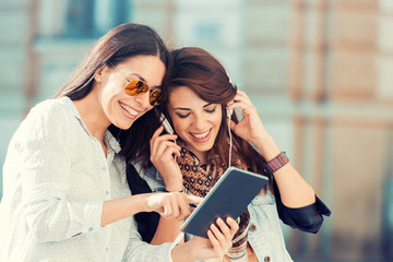 Two woman listening to music and relaxing in the city