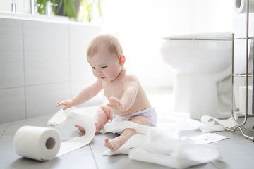 Fototapeta premium Toddler ripping up toilet paper in bathroom
