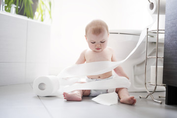 Toddler ripping up toilet paper in bathroom