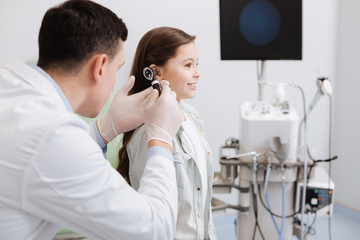 Attentive doctor holding otoscope in right hand