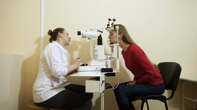 Young blond-haired woman examining her eyesight at the optometrist's. HD