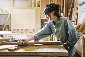 Young woman sanding wood in a workshop