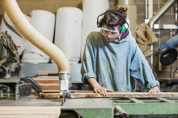 Young woman using machinery in a wood workshop