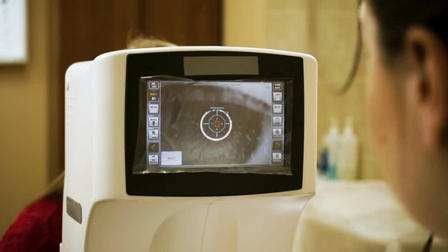 Young blond-haired woman examining her eyesight at the optometrist's. HD