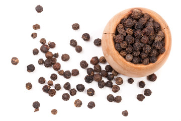 Black peppercorn in a wooden bowl isolated on white background. Top view