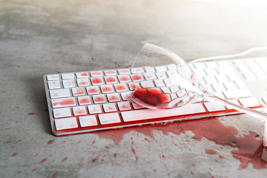 Red wine spilled over computer keyboard on concrete table