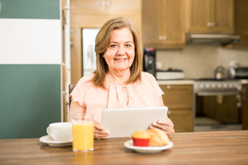 Obraz na płótnie Canvas Senior adult having breakfast holding a tablet