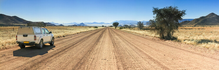 Pickup truck driving fast on long straight desert road