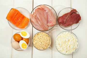 Proteins, fish, cheese, eggs, meat and chicken on a white wooden background