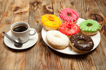 Obraz na płótnie Canvas Cup with coffee and donuts on a wooden background