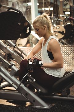 Fit woman using smartwatch on a machine