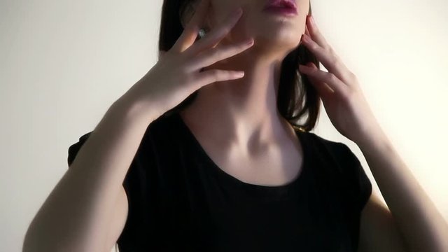 A woman holds her fingers over the face, neck, collarbone