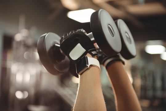 Hands of fit woman exercising with dumbbells