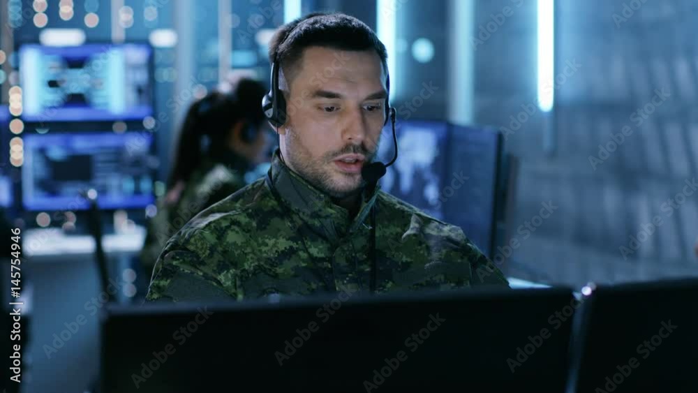 Leinwandbilder military technical support professional gives instructions using headset. he's in a monitoring room 