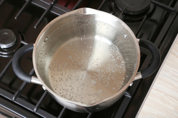 Water boiling into saucepan on the gas stove