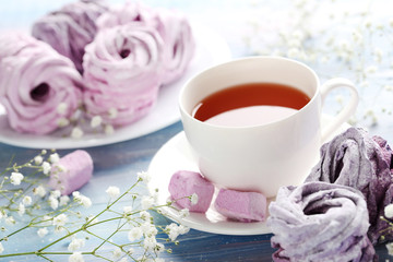 Fototapeta na wymiar Sweet zephyr with cup of tea on blue wooden table