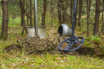 Metal detector, shovel, pot on the background of a pine forest